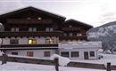 A cozy chalet in the snow with a warm light coming from the windows. Snow-covered mountains are visible in the background.
