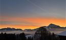 A beautiful sunrise over snow-covered mountains. The color palette ranges from orange to blue in the sky.