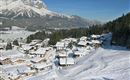 A snowy village in the Alps with colorful houses. Impressive mountains are visible in the background.