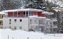 A modern building in the snow with red and white elements. Snow-covered trees are visible all around.