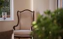 A comfortable armchair is placed in a bright room. In the background, a window with plants can be seen.