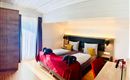 Een comfortabele slaapkamer met een groot tweepersoonsbed en gezellige kussens. De ruimte is licht en modern met een bureau en een kledingkast.