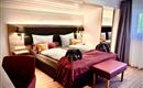 Een moderne slaapkamer met een groot bed en elegante kussens. De warme kleuren en houten elementen creëren een gezellige sfeer.