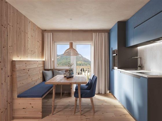 Ein modernes Esszimmer mit Holzverkleidung und großen Fenstern. Der Tisch ist gedeckt und der Blick auf die Berge ist sichtbar.