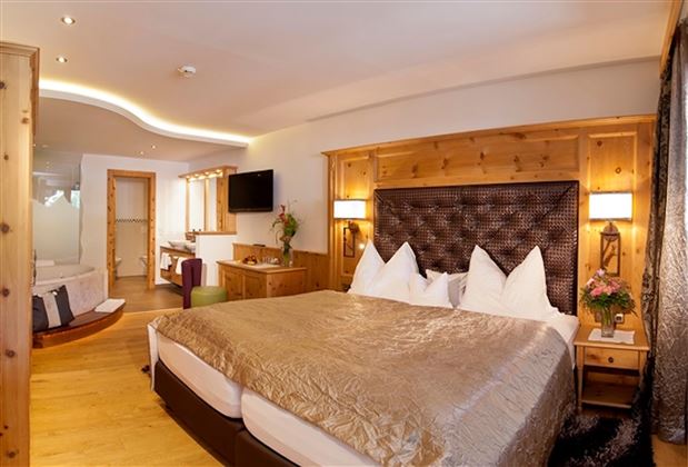 A cozy bedroom with a large double bed and elegant wooden furniture. The atmosphere is warm and inviting, perfect for relaxing.