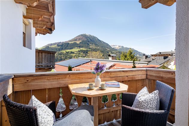 Ein schöner Balkon mit Blick auf die Berge. Ein Tisch mit Kaffeetassen und gemütlichen Stühlen lädt zum Entspannen ein.