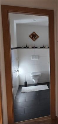 Een moderne badkamer met een eenvoudig ontwerp. Op de achtergrond zijn het toilet en de wasbak zichtbaar.