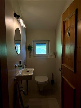 A modern bathroom with a sink, a toilet, and a small window. The room is bright and has a cozy atmosphere.