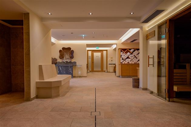 A bright and inviting wellness area with modern elements. On the left side, there are seating areas and a sauna in the corner.