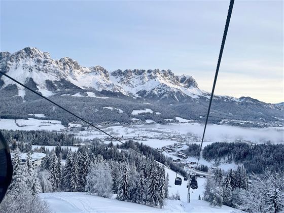 Een mooie winterlandschap met besneeuwde bergen en dennenbomen. Een kabelbaan trekt over het landschap.