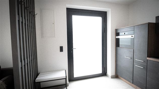 Ein modern eingerichteter Eingangsbereich mit einem großen Fenster und einer hellen Wandfarbe. Auf der linken Seite stehen ein Schuhregal und eine elegante Sitzbank.