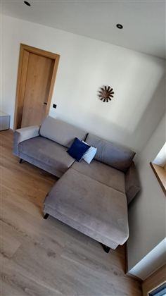 Ein gemütliches, modernes Wohnzimmer mit einem hellen Sofa und einem dekorativen Kissen.