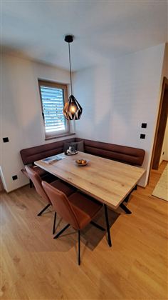 Ein moderner Essbereich mit einem Holztisch und eleganten Stühlen. Die warmen Töne und das natürliche Licht schaffen eine einladende Atmosphäre.