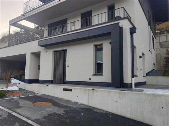 Ein modernes Wohnhaus mit klaren Linien und einer minimalistischen Fassade. Die Umgebung ist gut gepflegt und hat eine gepflasterte Einfahrt.