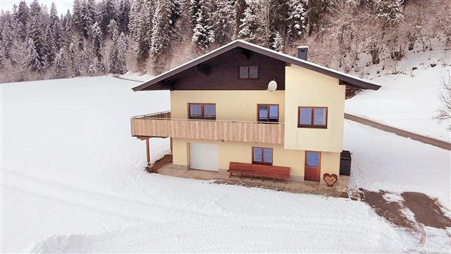 Een gezellig huis in een besneeuwd landschap. Omringd door bomen en verse sneeuw, creëert het een uitnodigende sfeer.