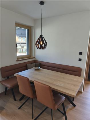 Ein gemütlicher Essbereich mit einem holzigen Tisch und bequemen Stühlen. Eine moderne Pendelleuchte sorgt für angenehmes Licht.