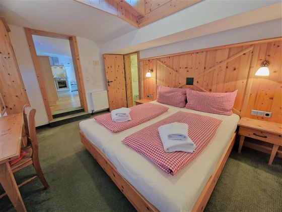A cozy bedroom with a large bed and wood paneling. The room is bright and inviting, with a table and chairs.