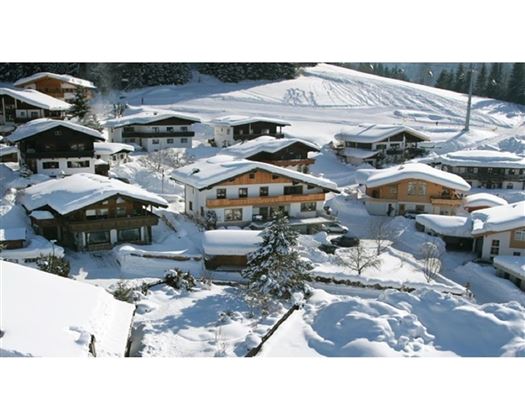 A picturesque village in the snow with traditional chalets and snowy landscapes. The houses are surrounded by a beautiful winter landscape.
