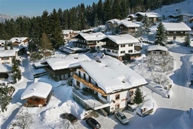 A picturesque mountain landscape with snow-covered houses and trees. The area is calm and idyllic.
