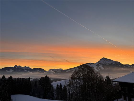 A beautiful sunrise over snow-covered mountains. The color palette ranges from orange to blue in the sky.