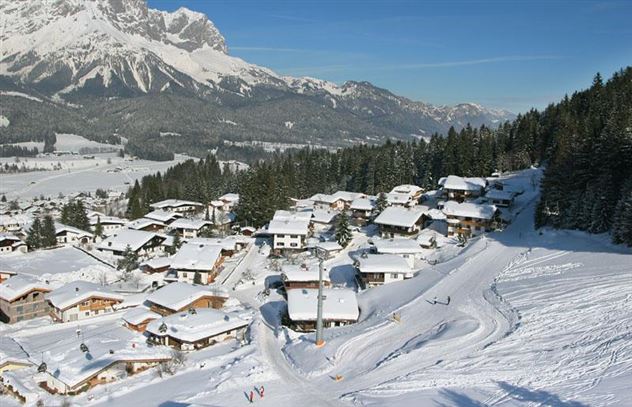 A snowy village in the Alps with colorful houses. Impressive mountains are visible in the background.
