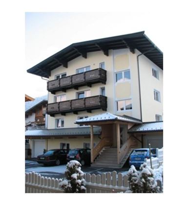 Een meerlaagse woning met lichte muren en balkons. Het is bedekt met sneeuw en bevindt zich in een rustige omgeving.