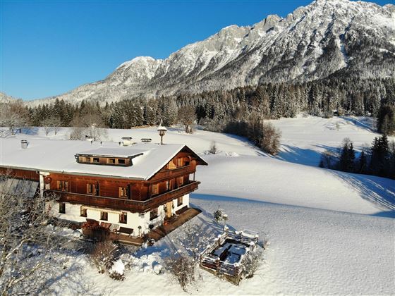 Ein charmantes Holzhaus im Schnee mit Blick auf majestätische Berge. Die Umgebung ist winterlich und, mit weißem Schnee bedeckt.