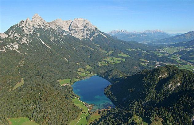 A picturesque landscape with mountains and a clear lake in the middle. Surrounded by green meadows and forests, the beauty of nature unfolds.