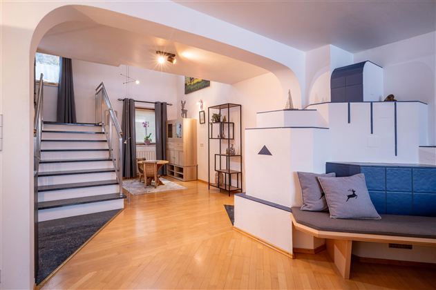 Ein modernes Wohnzimmer mit einem großen Fernseher und einem bequemen Sofa. Die Wände sind hell und der Boden ist aus Holz.