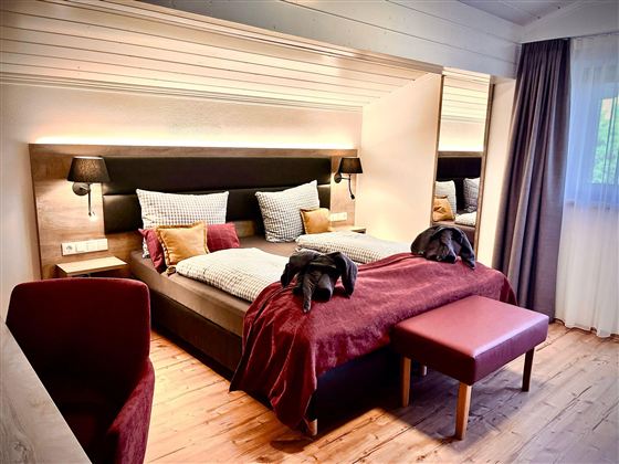 Een moderne slaapkamer met een groot bed en elegante kussens. De warme kleuren en houten elementen creëren een gezellige sfeer.