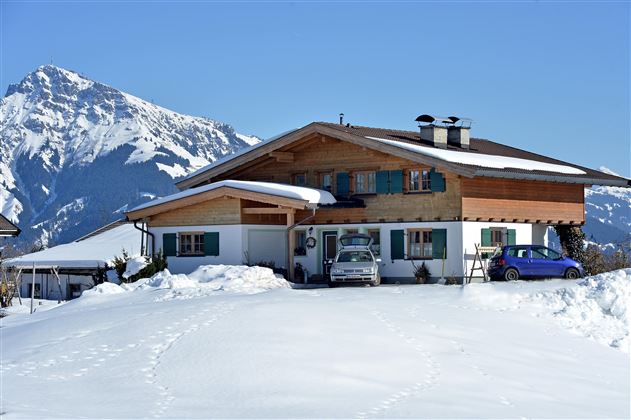 Ein schönes Haus in den Alpen, umgeben von Schnee. Im Hintergrund sind majestätische Berge zu sehen.